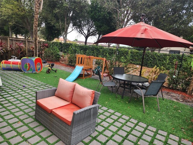 229 NE 36th Ter, Homestead, FL 33033 - fenced backyard with a playground, a patio area, and an outdoor living space