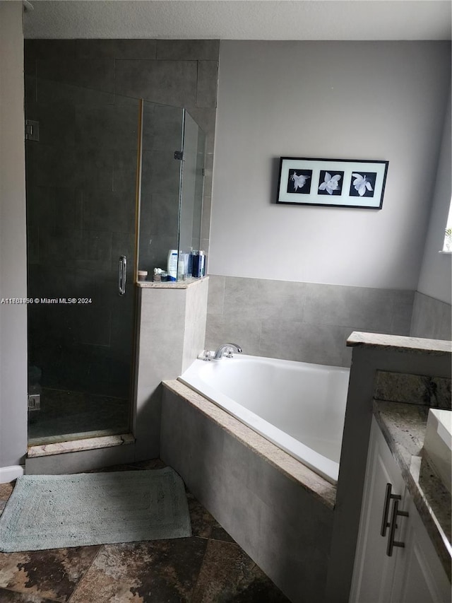 bathroom with plus walk in shower, a textured ceiling, and vanity