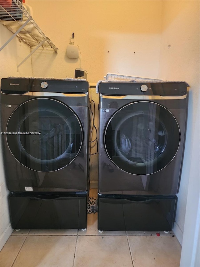 clothes washing area featuring tile patterned floors and washing machine and clothes dryer