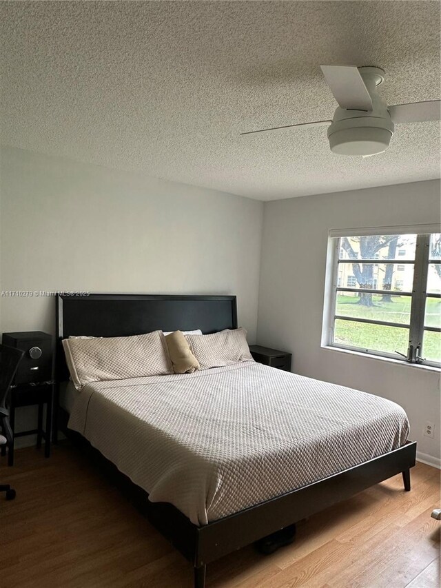 bedroom with hardwood / wood-style flooring, ceiling fan, and a textured ceiling