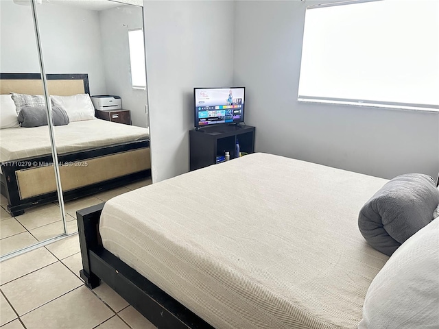 bedroom featuring light tile patterned floors, a closet, and multiple windows