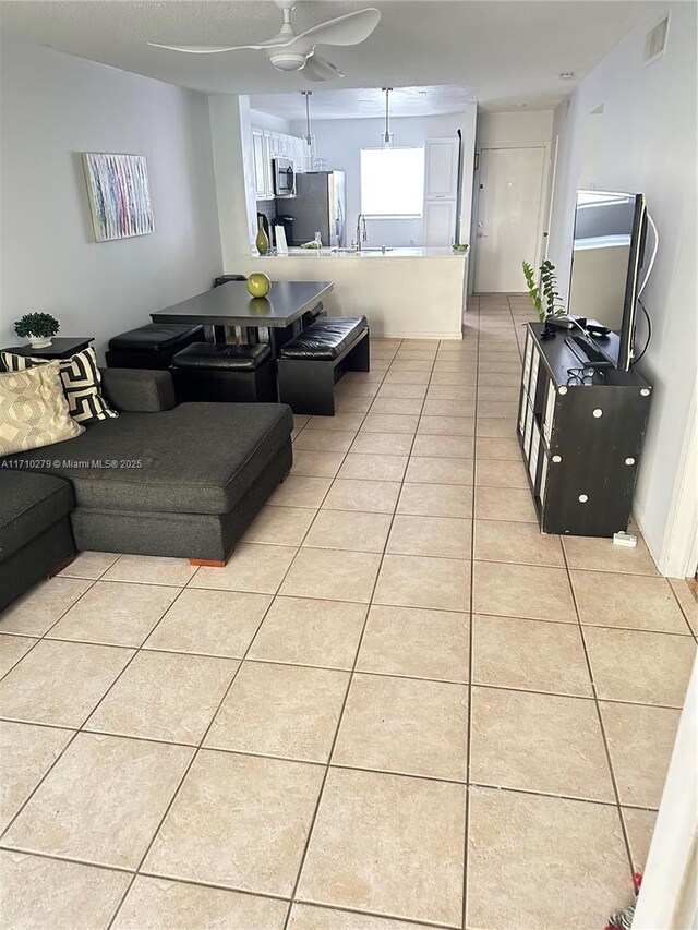 tiled living room with ceiling fan and sink