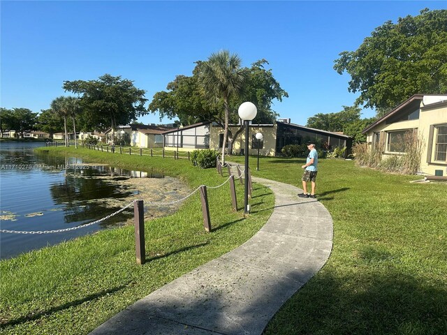 view of home's community with a water view and a lawn