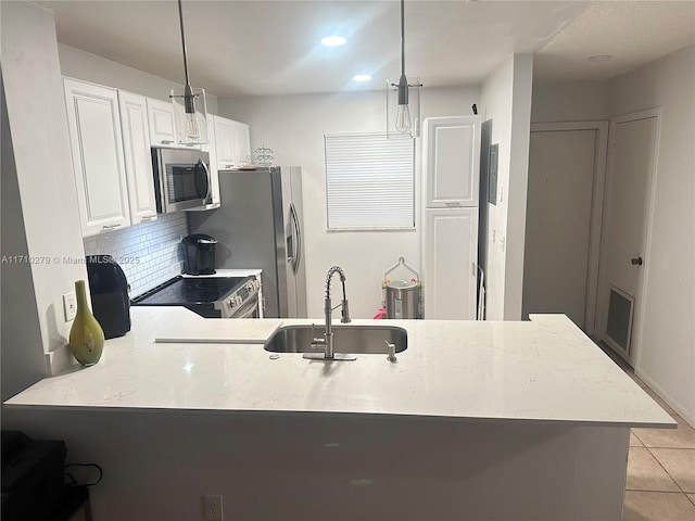 kitchen with kitchen peninsula, sink, pendant lighting, and appliances with stainless steel finishes