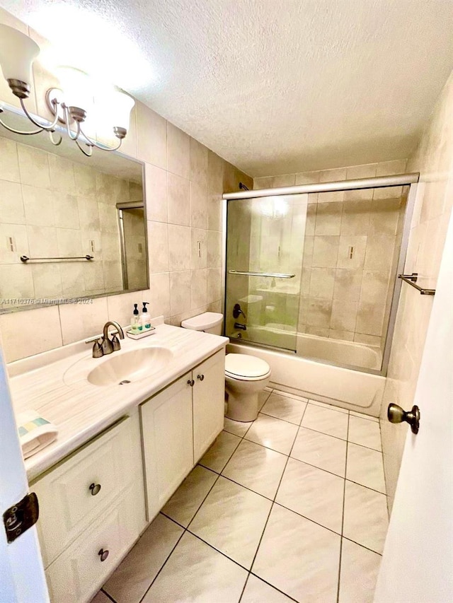 full bathroom with tile patterned floors, vanity, a textured ceiling, tile walls, and enclosed tub / shower combo