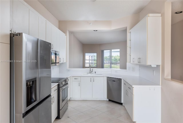 kitchen featuring white cabinets, sink, light tile patterned floors, and stainless steel appliances