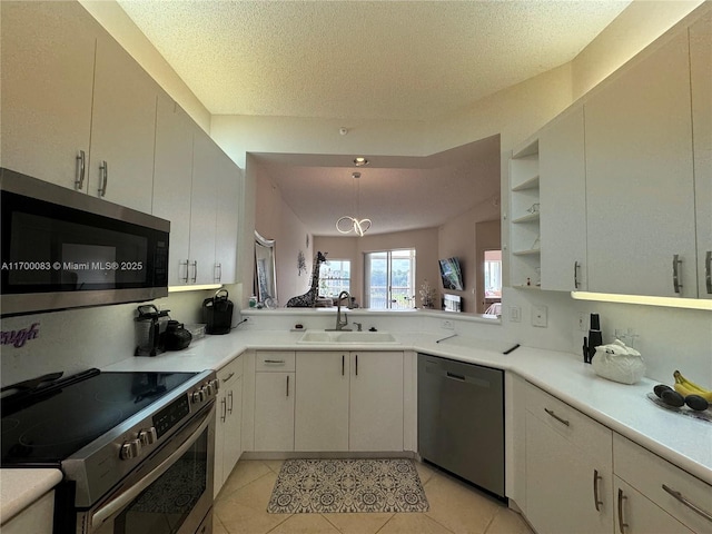 kitchen featuring sink, stainless steel appliances, kitchen peninsula, a textured ceiling, and light tile patterned flooring