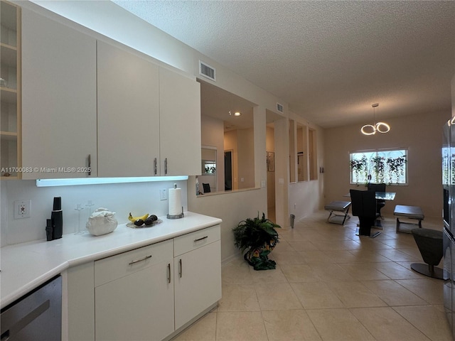 kitchen featuring a textured ceiling, white cabinetry, and hanging light fixtures