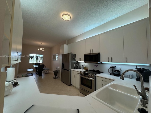 kitchen with white cabinetry, sink, stainless steel appliances, a textured ceiling, and light tile patterned floors