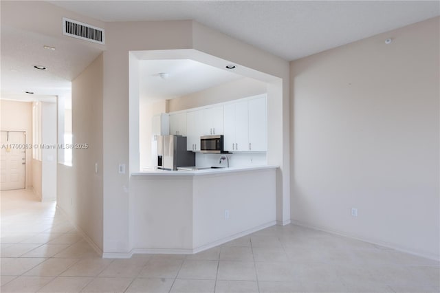 kitchen featuring a textured ceiling, white cabinets, stainless steel appliances, and light tile patterned floors