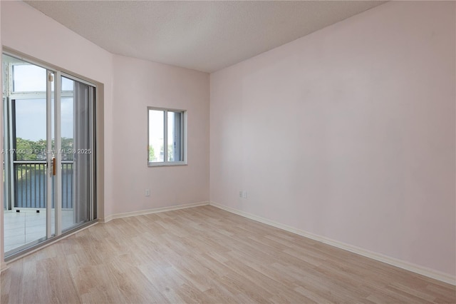 unfurnished room with light wood-type flooring and a textured ceiling