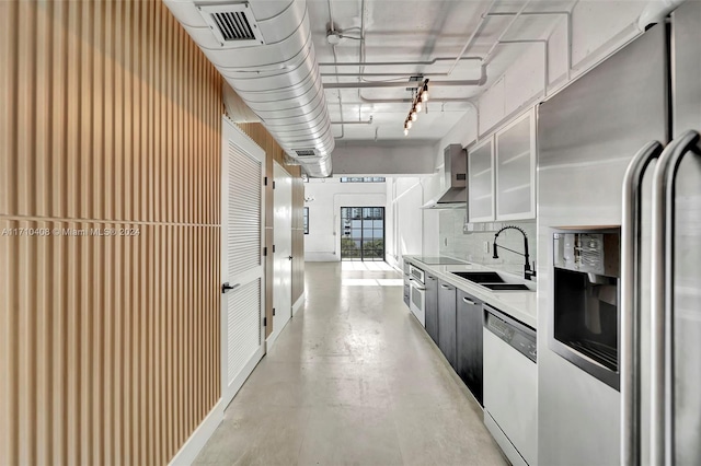 kitchen with tasteful backsplash, sink, wall chimney range hood, and appliances with stainless steel finishes