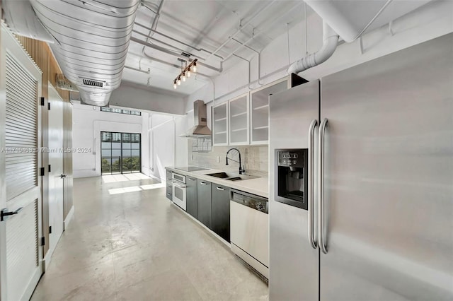 kitchen with wall chimney range hood, stainless steel appliances, tasteful backsplash, and sink