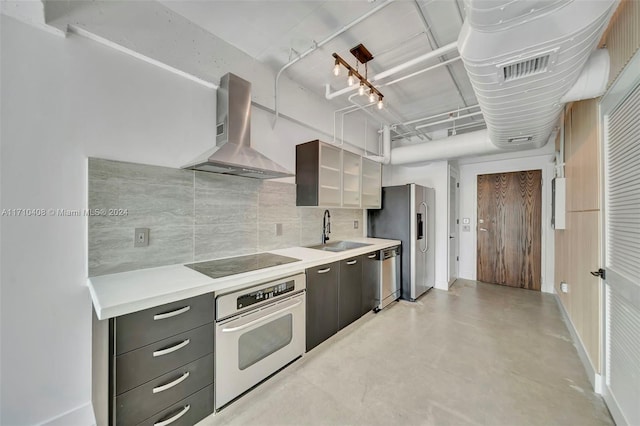 kitchen featuring decorative backsplash, stainless steel appliances, wall chimney exhaust hood, and sink