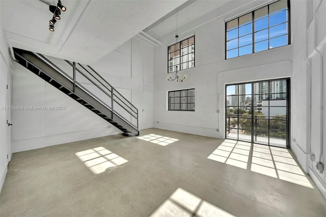 unfurnished living room with a towering ceiling and concrete floors