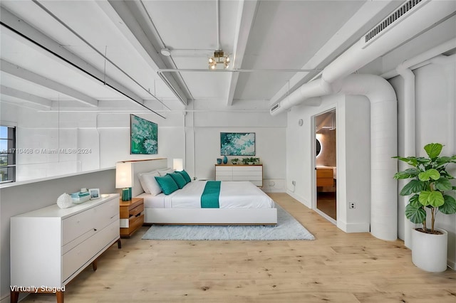 bedroom featuring connected bathroom and light hardwood / wood-style flooring