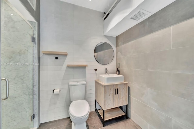 bathroom with vanity, a shower with door, tile patterned floors, and tile walls