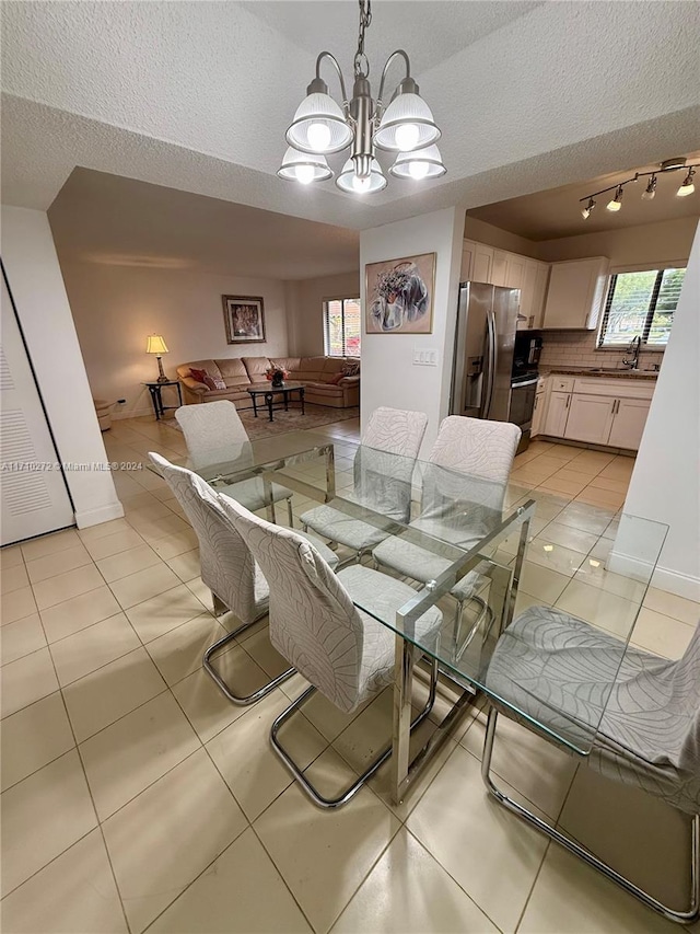 dining space with a chandelier, light tile patterned floors, a textured ceiling, and sink