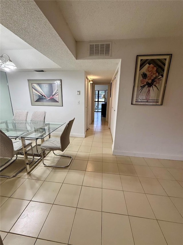 dining space featuring light tile patterned flooring and a textured ceiling