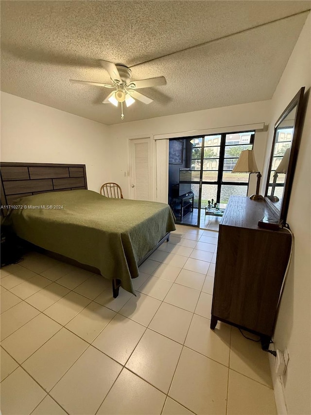 tiled bedroom featuring ceiling fan, access to exterior, and a textured ceiling