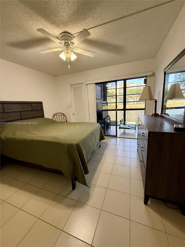 tiled bedroom featuring ceiling fan, access to exterior, and a textured ceiling