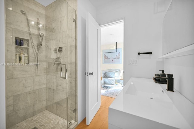 bathroom featuring hardwood / wood-style flooring, an enclosed shower, and sink