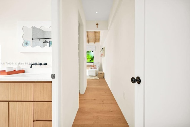 corridor with sink and light hardwood / wood-style flooring