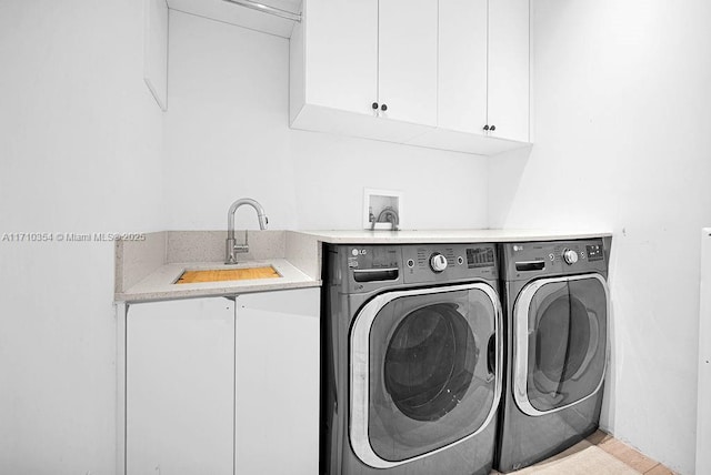 laundry area featuring washer and clothes dryer, cabinets, and sink