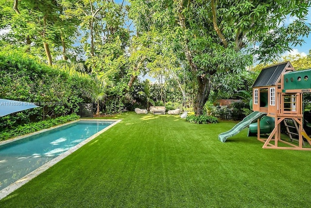 view of pool with a lawn and a playground