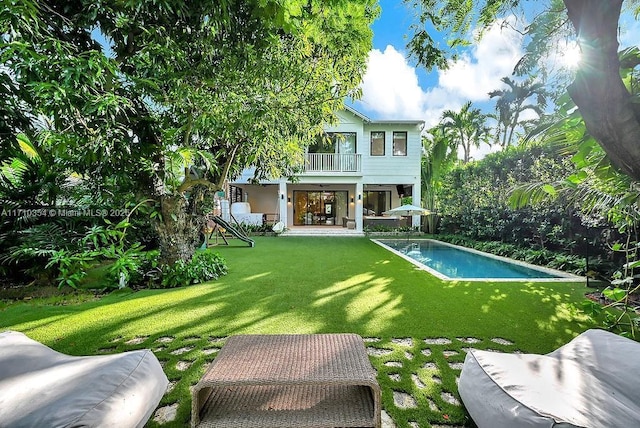 back of house with a balcony, a patio area, and a lawn