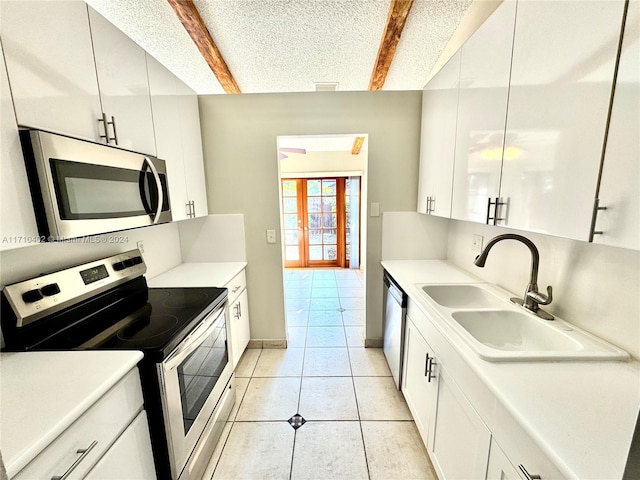 kitchen featuring beam ceiling, sink, white cabinets, and appliances with stainless steel finishes