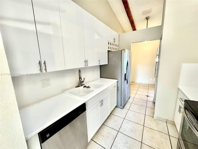 kitchen with stainless steel appliances, sink, light tile patterned floors, lofted ceiling with beams, and white cabinets