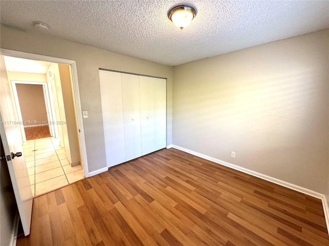 unfurnished bedroom featuring a closet, hardwood / wood-style floors, and a textured ceiling