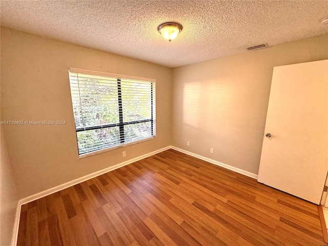 unfurnished room with hardwood / wood-style floors and a textured ceiling