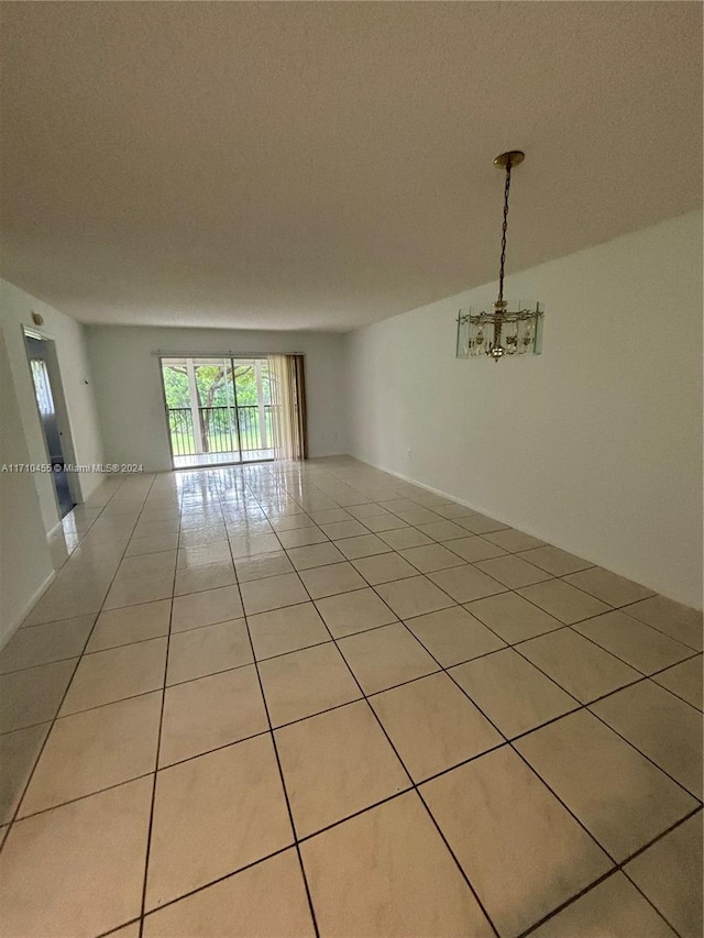 tiled empty room featuring a notable chandelier