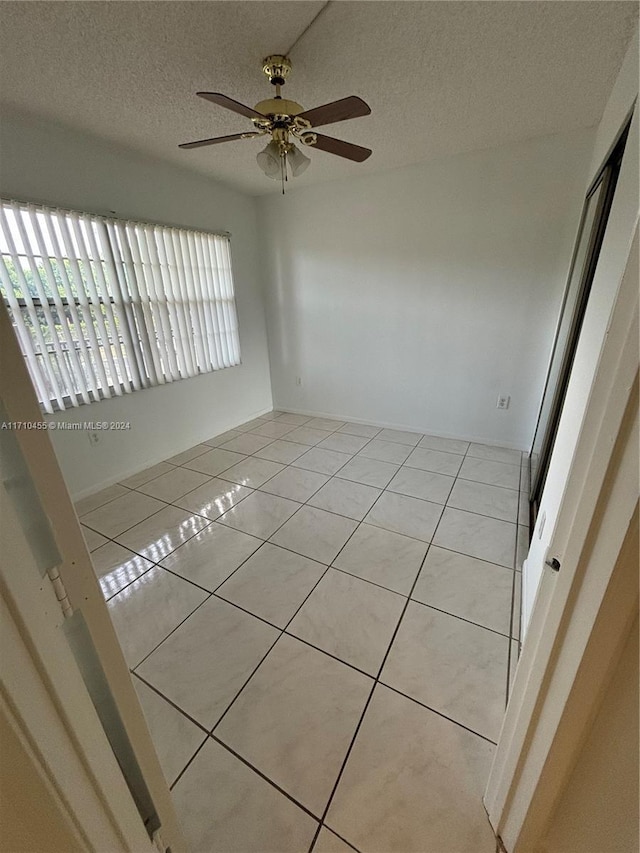 tiled empty room with a textured ceiling and ceiling fan