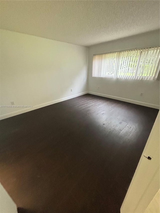 empty room with wood-type flooring and a textured ceiling