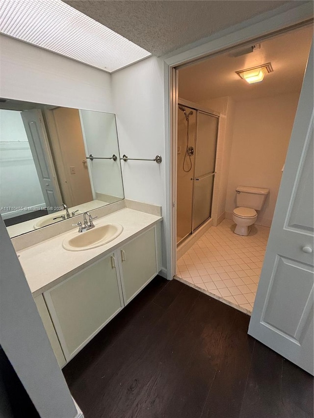 bathroom with an enclosed shower, a textured ceiling, vanity, hardwood / wood-style flooring, and toilet