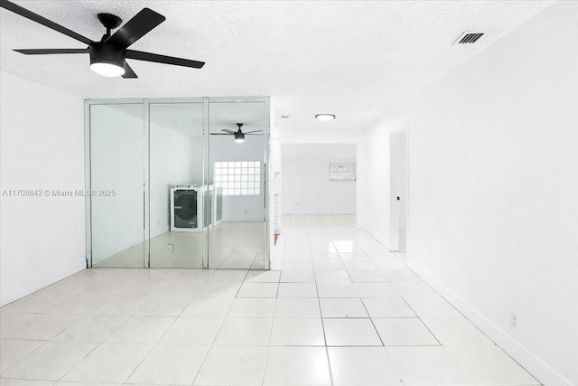 unfurnished bedroom with a textured ceiling, light tile patterned floors, visible vents, and a ceiling fan