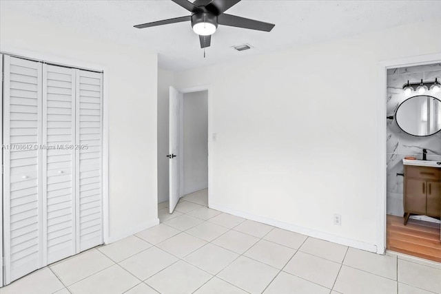 unfurnished bedroom with a closet, visible vents, a ceiling fan, light tile patterned flooring, and baseboards