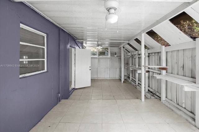 corridor with light tile patterned floors, lofted ceiling, and wood walls