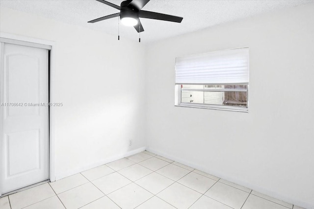 empty room featuring a ceiling fan, a textured ceiling, and light tile patterned floors