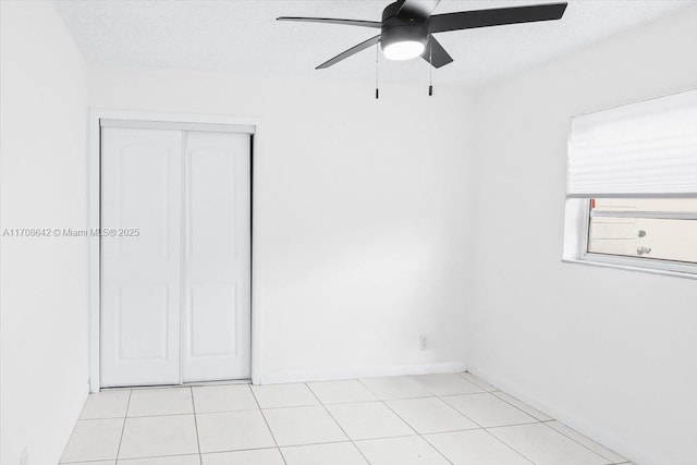 unfurnished room with light tile patterned floors, a textured ceiling, and a ceiling fan