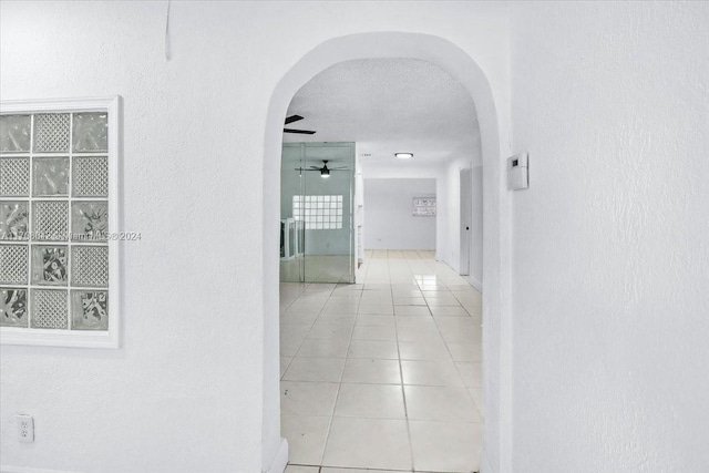 hall featuring light tile patterned floors and a textured ceiling