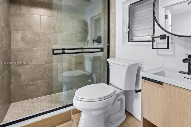 full bathroom featuring a walk in shower, toilet, wood finished floors, and vanity