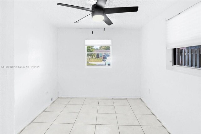 unfurnished room with a textured ceiling, ceiling fan, and light tile patterned floors