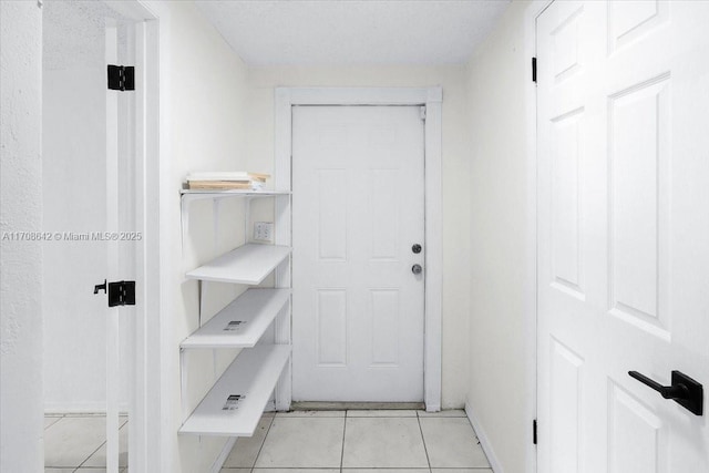 entryway with light tile patterned flooring and baseboards