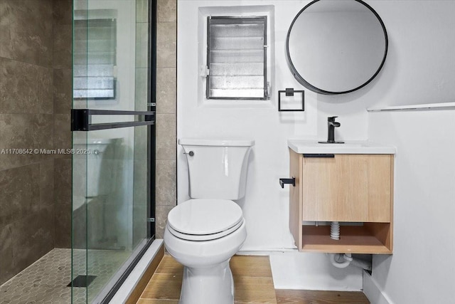 bathroom with a stall shower, vanity, toilet, and wood finished floors