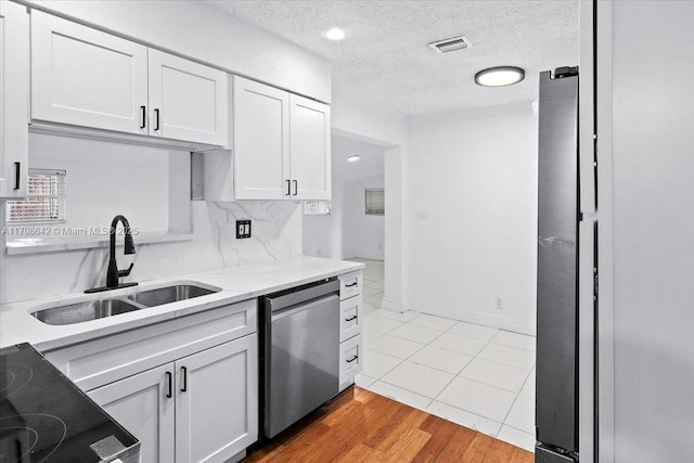 kitchen with a textured ceiling, a sink, visible vents, white cabinetry, and dishwasher