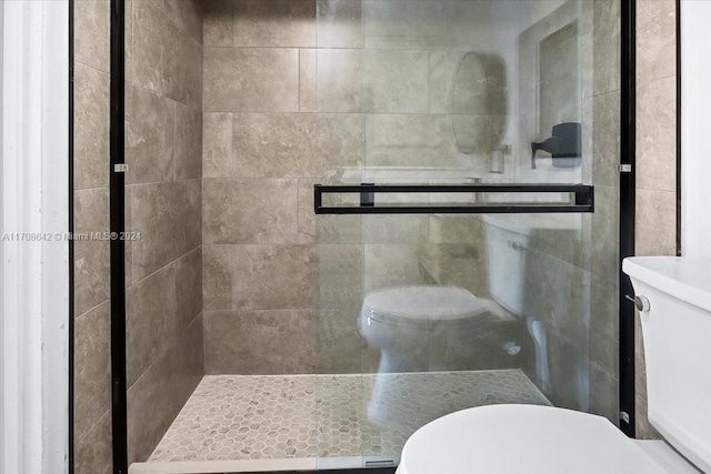 bathroom with a shower with shower door and toilet